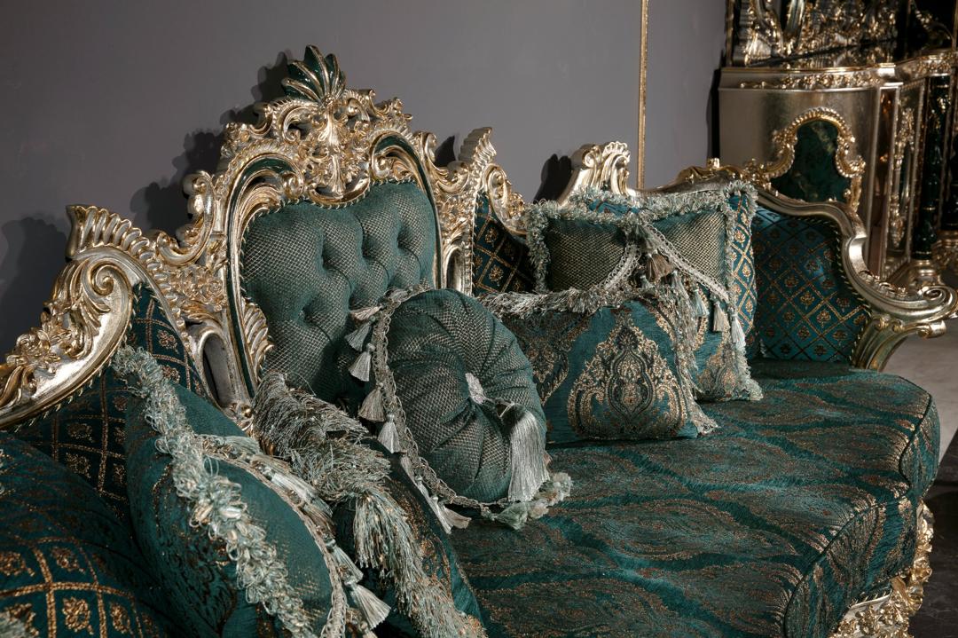 Luxurious teal sofa with gold accents and decorative pillows against a dark background