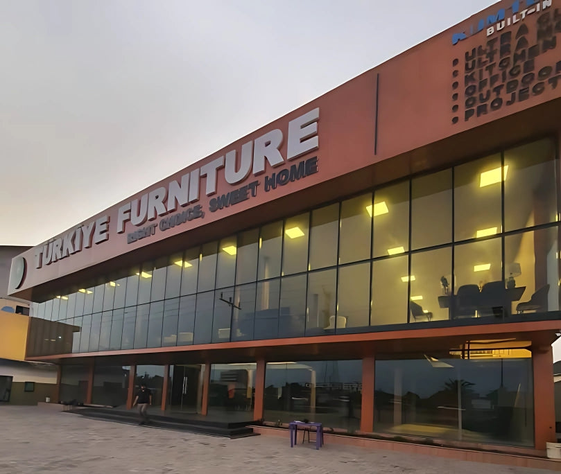 Furniture store with large glass windows and a prominent sign on a paved area.