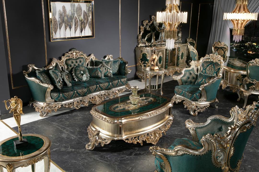 A luxurious living room set featuring emerald green upholstery and gold or silver-leafed carvings, including a sofa, armchairs, and a coffee table.